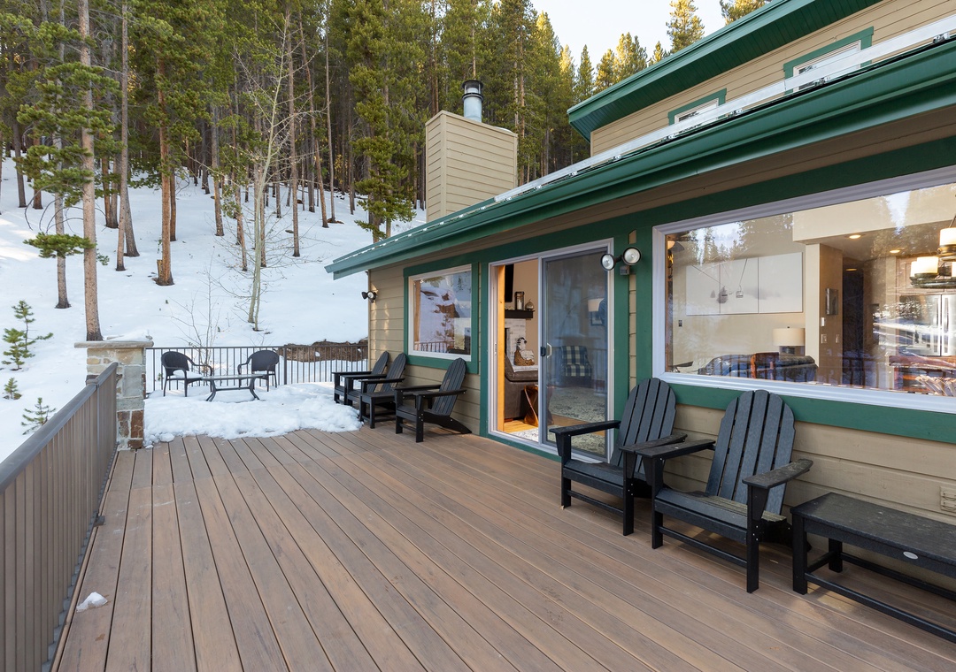 Step onto your private deck overlooking a pristine winter forest, where warm Adirondack chairs await cozy evening moments.