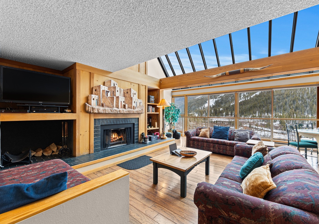 Relax in your spacious living room with crackling fireplace, soaring ceilings, and stunning mountain views through floor-to-ceiling windows.