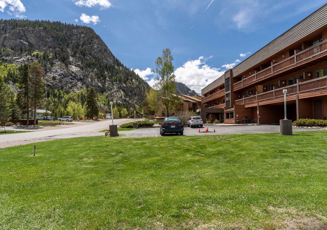 Property nestled against dramatic mountain backdrop with convenient parking and manicured grounds in scenic alpine setting.