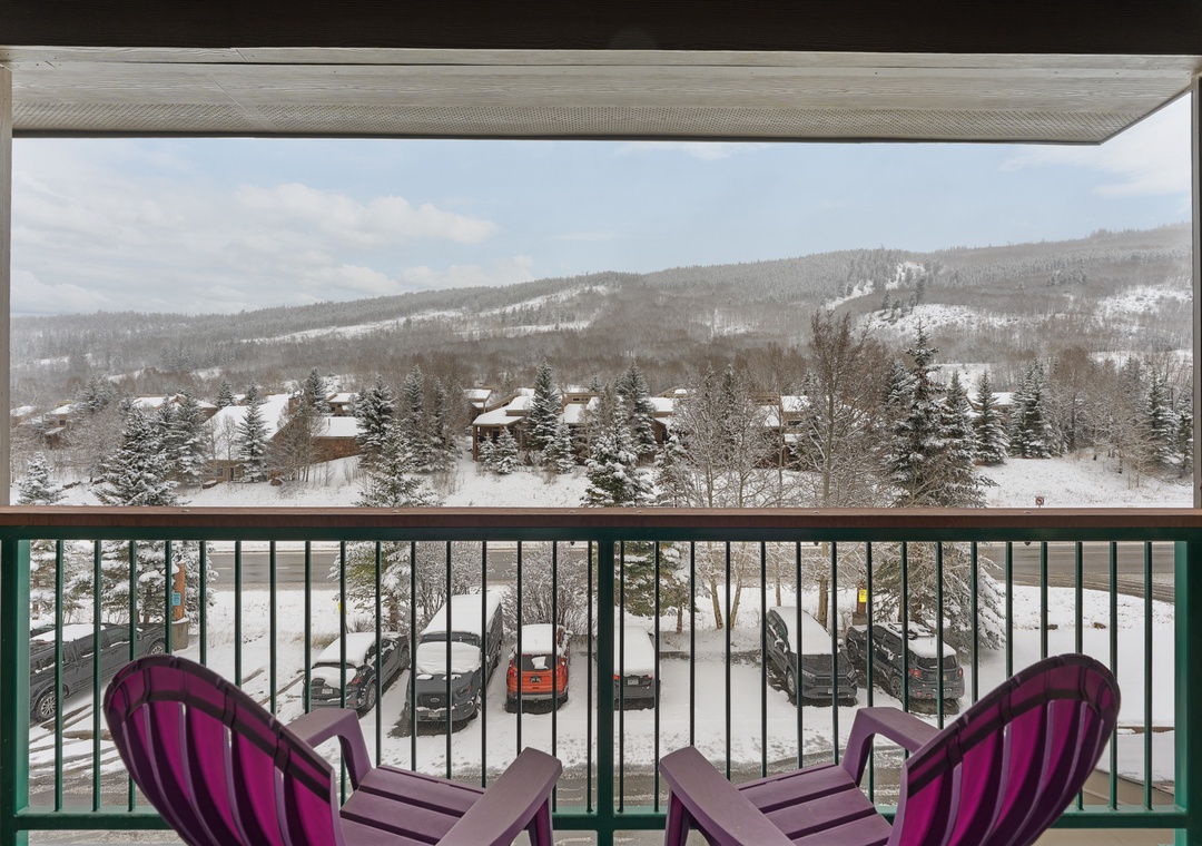 A framed winter landscape stretches before you, showcasing snow-dusted mountain slopes and evergreen forests, captured from your private balcony seating area.