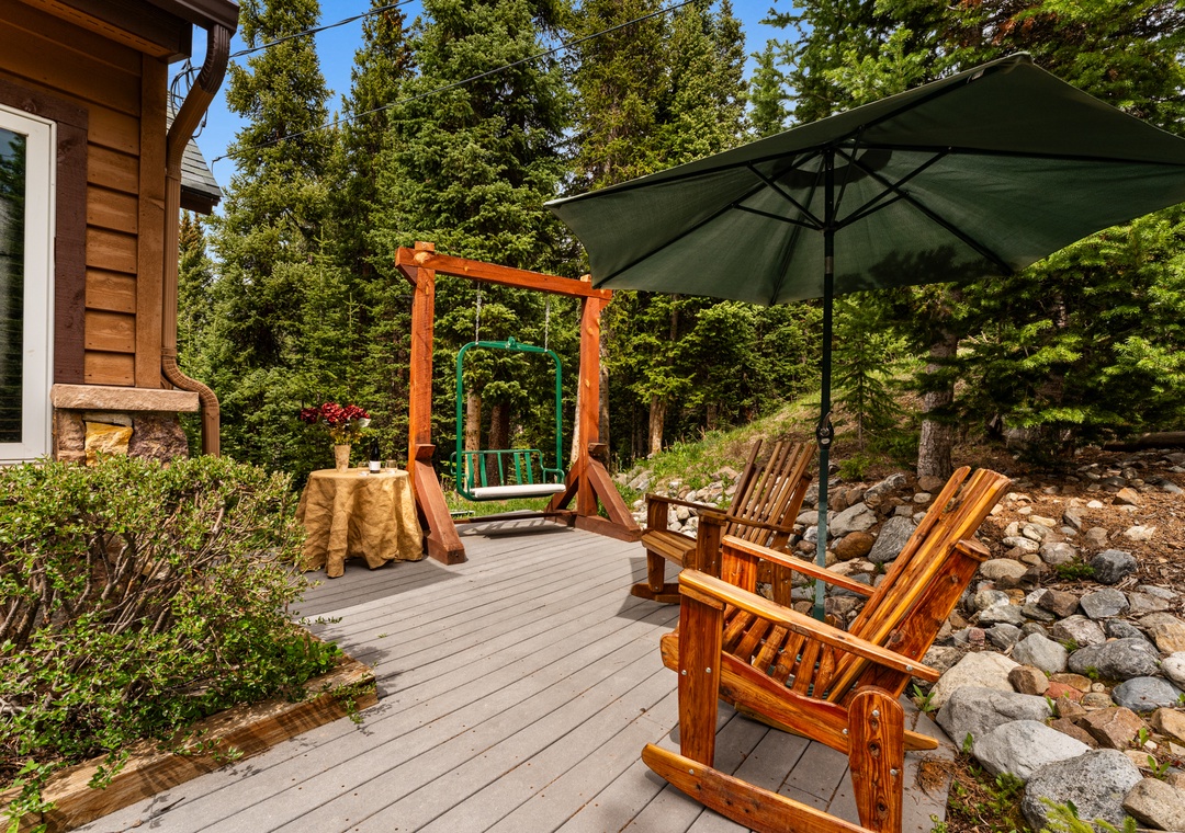 Your private deck offers handcrafted wooden seating shaded by an umbrella, a charming garden swing, and forest views for peaceful outdoor relaxation.