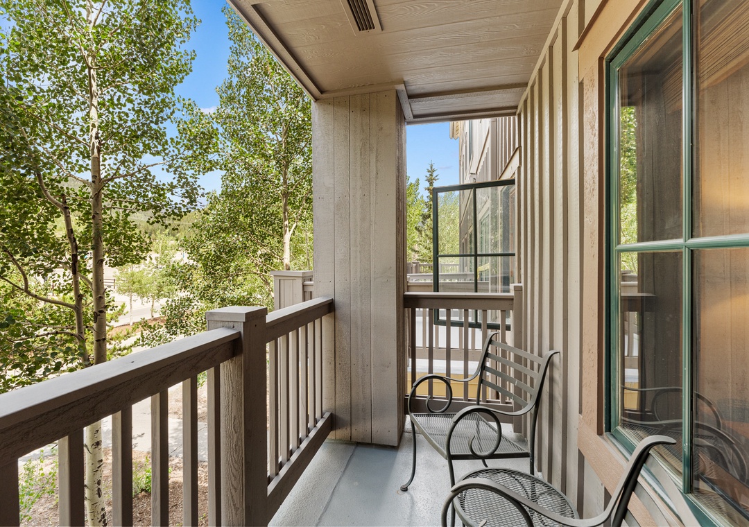 Relax on your private balcony with comfortable seating while enjoying peaceful tree-lined views and fresh mountain air.