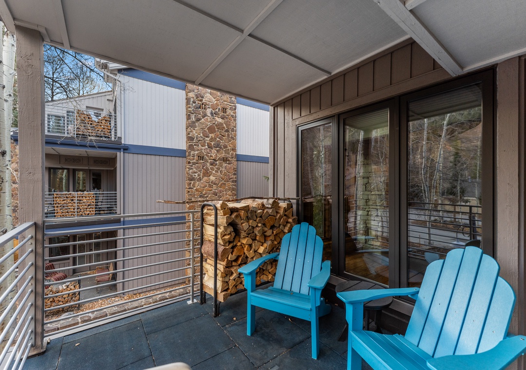 Relax on your private balcony with bright turquoise chairs and cozy firewood stack, perfect for mountain evenings.