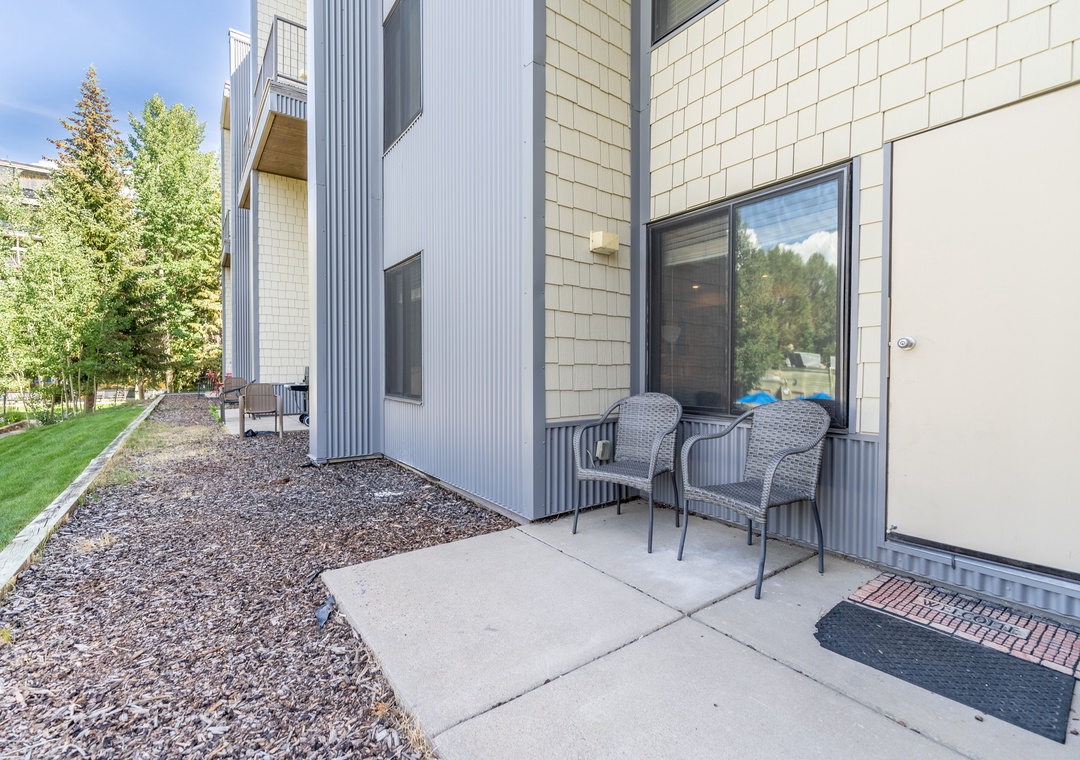 Modern property entrance with private patio seating area in a quiet residential neighborhood.