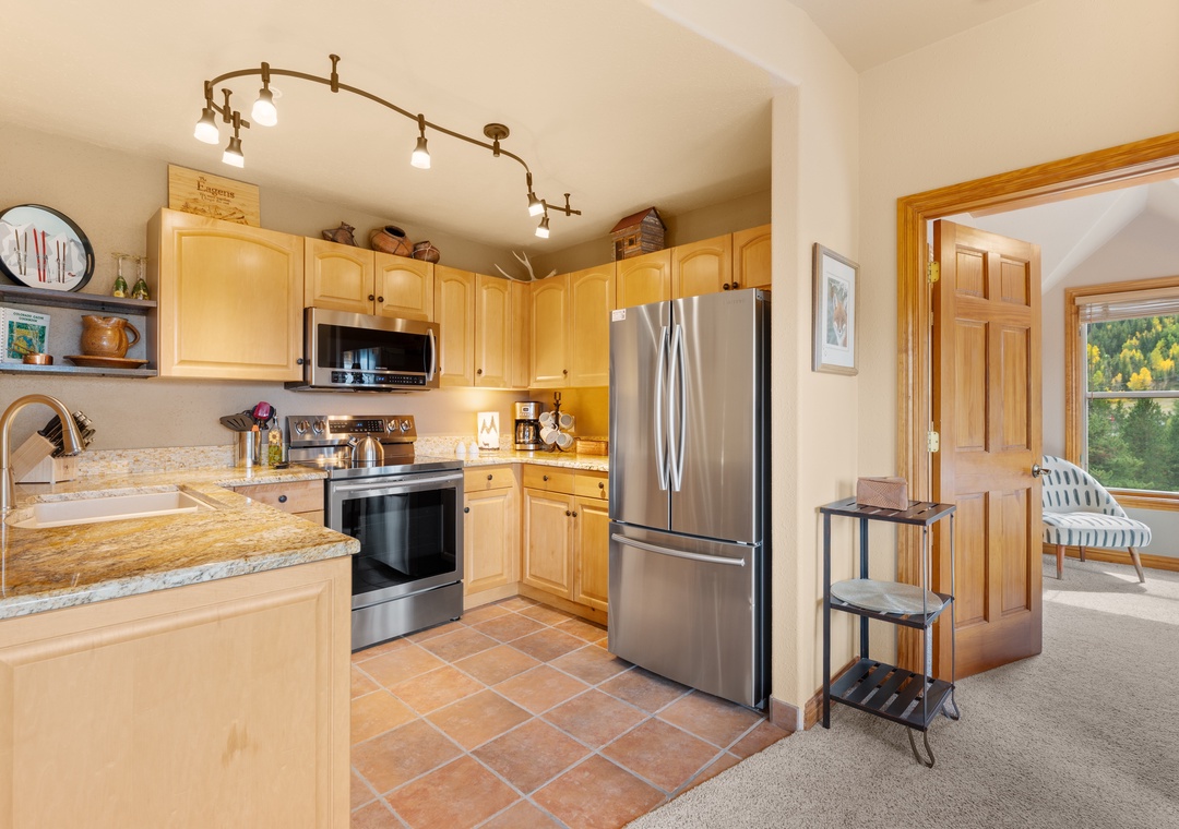 Step into your fully equipped kitchen with modern appliances and warm wood cabinetry, where you'll love preparing meals with forest views just beyond the doorway.