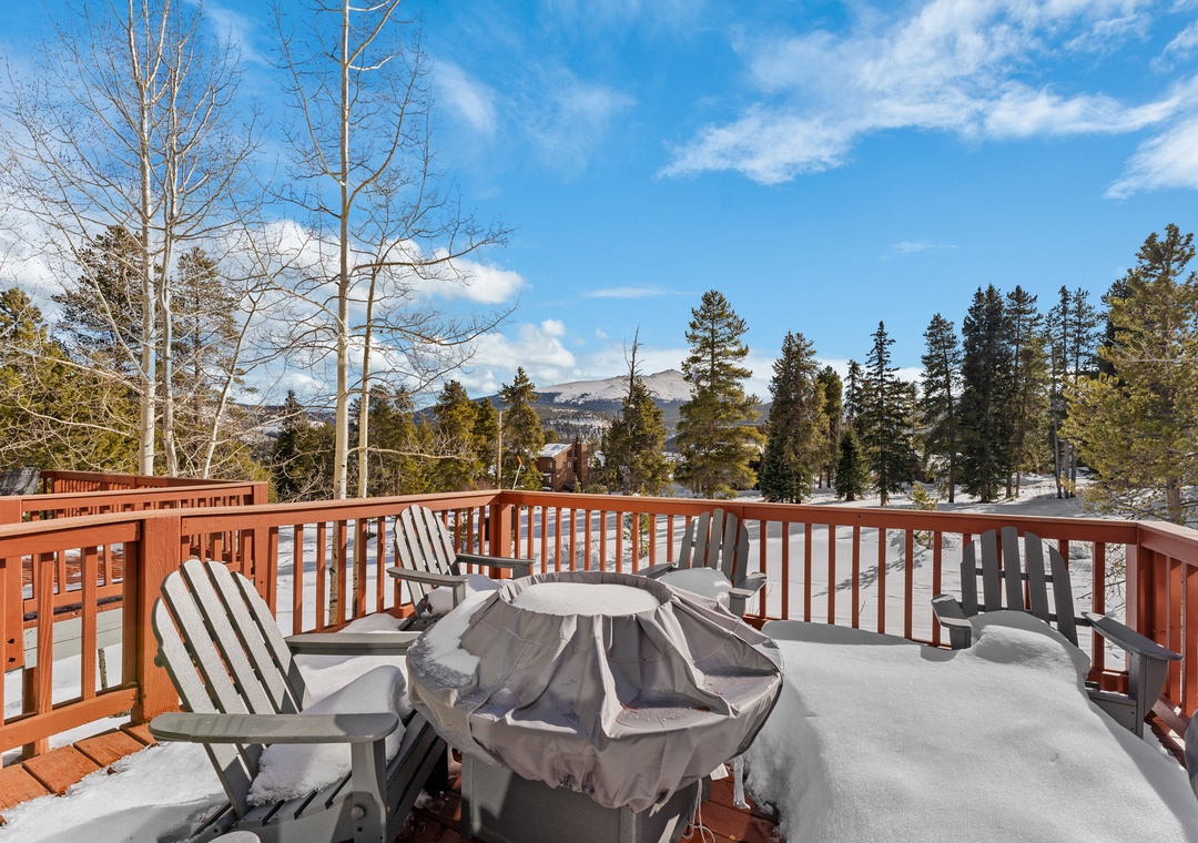 Snowy deck with mountain views and covered grill awaits your winter getaway moments.