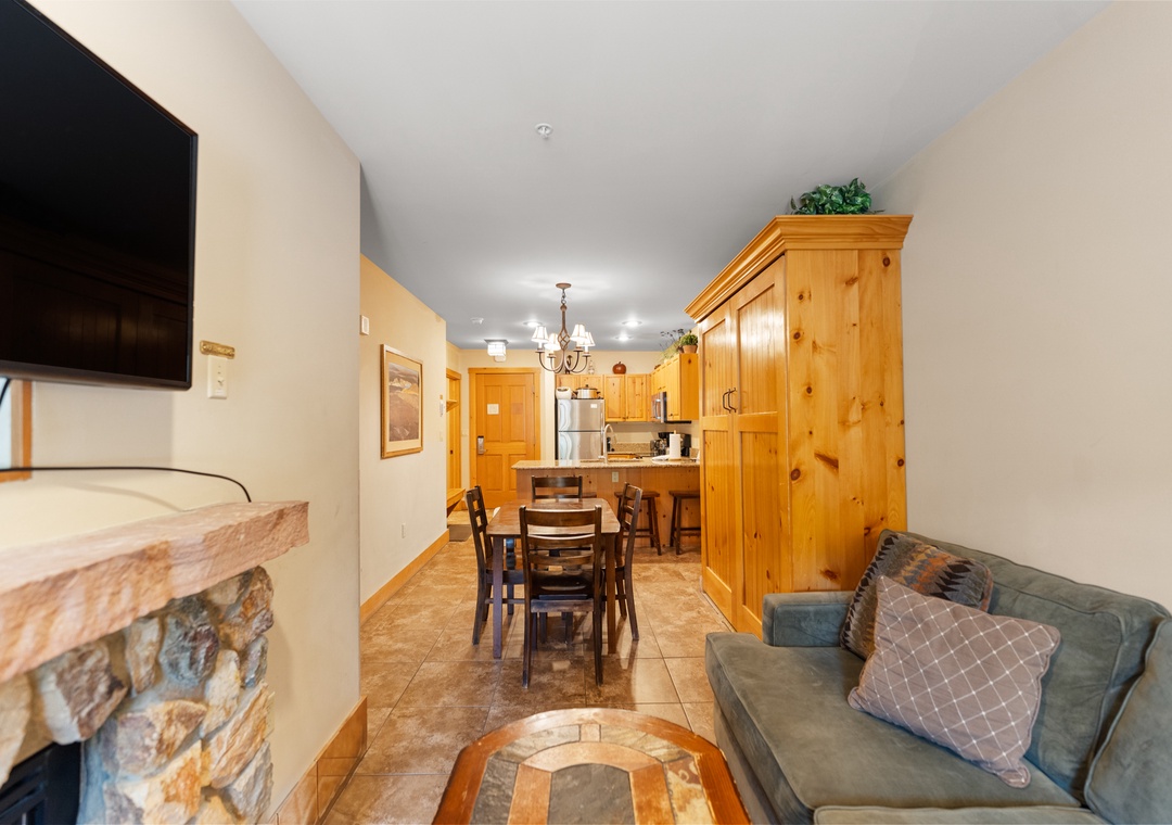 Relax in your cozy living space with warm wood accents, stone fireplace, and fully equipped kitchen—perfect for unwinding after mountain adventures.