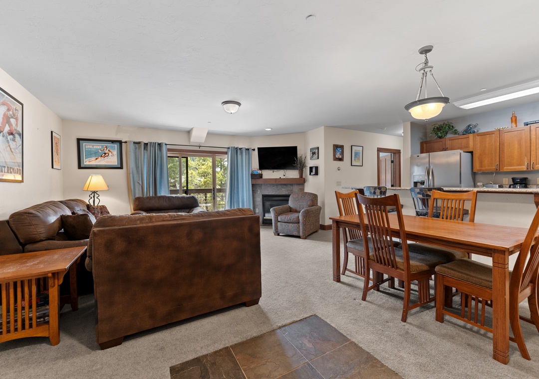 Settle into your spacious open-concept living area, where cozy leather seating flows into a dining space perfect for family meals. Natural light floods through large windows, while the fireplace adds warmth for mountain evenings.