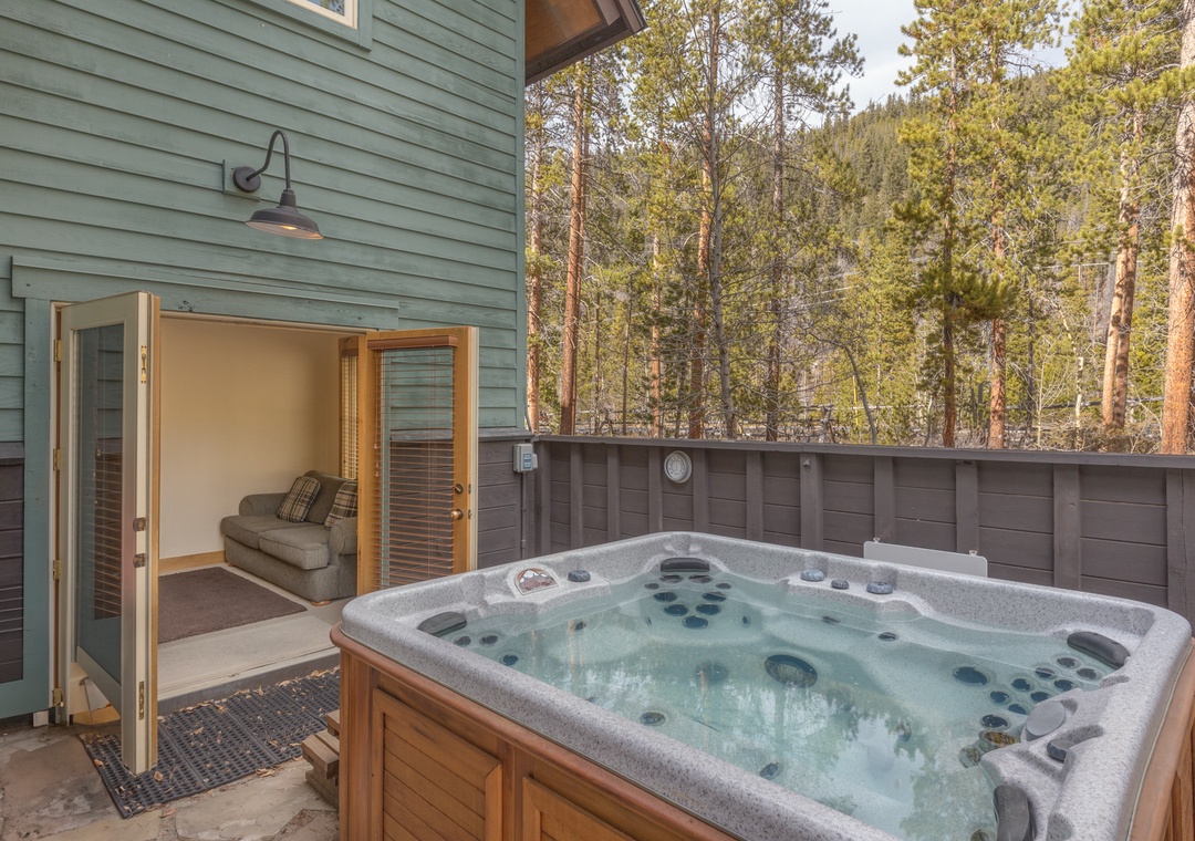 Step into your private sanctuary where bubbling jets invite relaxation beneath the forest canopy on this serene outdoor deck.