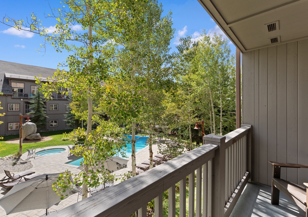 This private balcony offers a serene view of the shared pool and hot tub, framed by lush aspen trees and the surrounding neighborhood—a perfect spot to unwind with morning coffee.