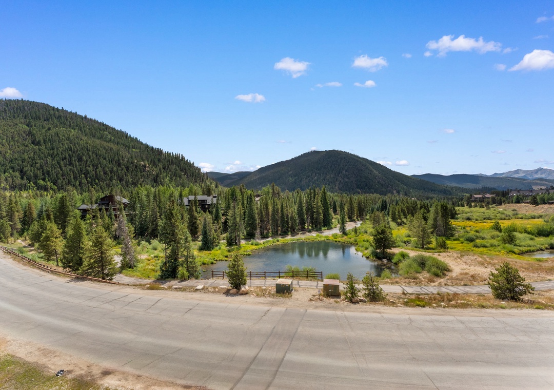 Mountain landscape surrounds this peaceful pond area, with forested hills creating a scenic backdrop for the property's natural setting.