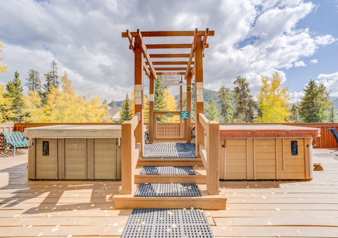 Outdoor hot tub area with wooden pergola surrounded by stunning autumn foliage and mountain views.