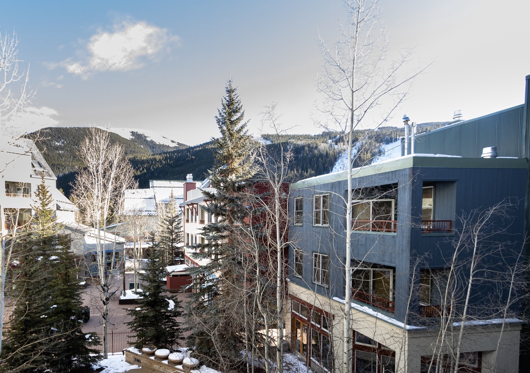 Winter mountain village setting with snow-covered peaks and residential buildings creating a serene alpine atmosphere.