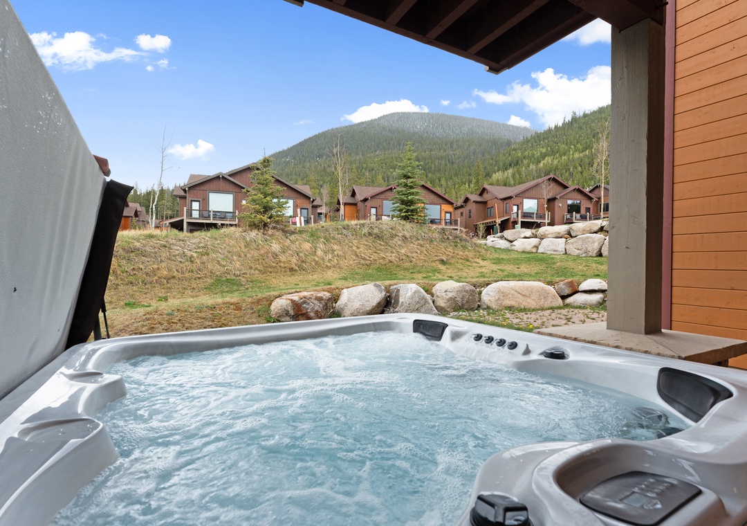 A private hot tub awaits under a covered patio, offering stunning mountain views and ultimate relaxation after your alpine adventures.