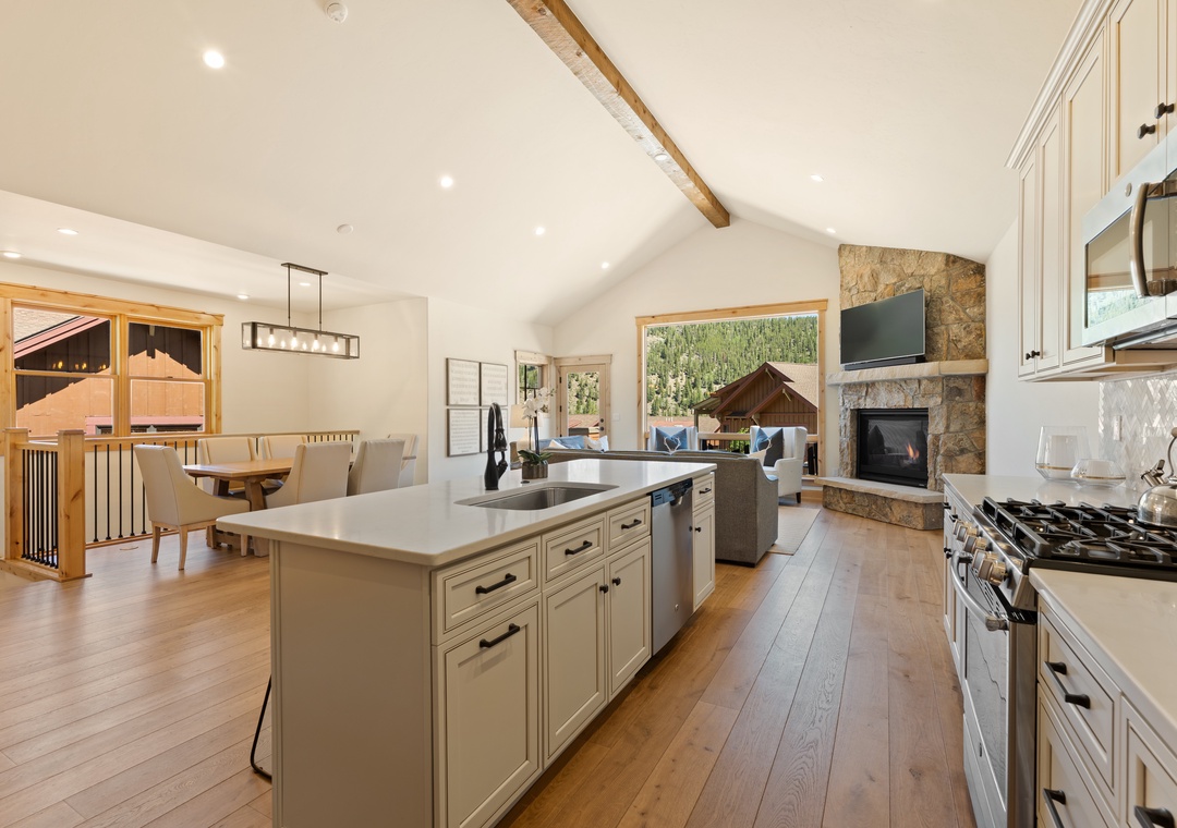 Imagine preparing meals in this spacious kitchen with its island workspace, designer appliances, and cozy stone fireplace—your perfect mountain retreat for cooking and gathering with loved ones.