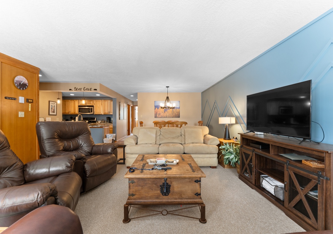 Relax in your spacious living room with plush leather seating, large TV, and rustic mountain decor creating the perfect après-ski retreat.