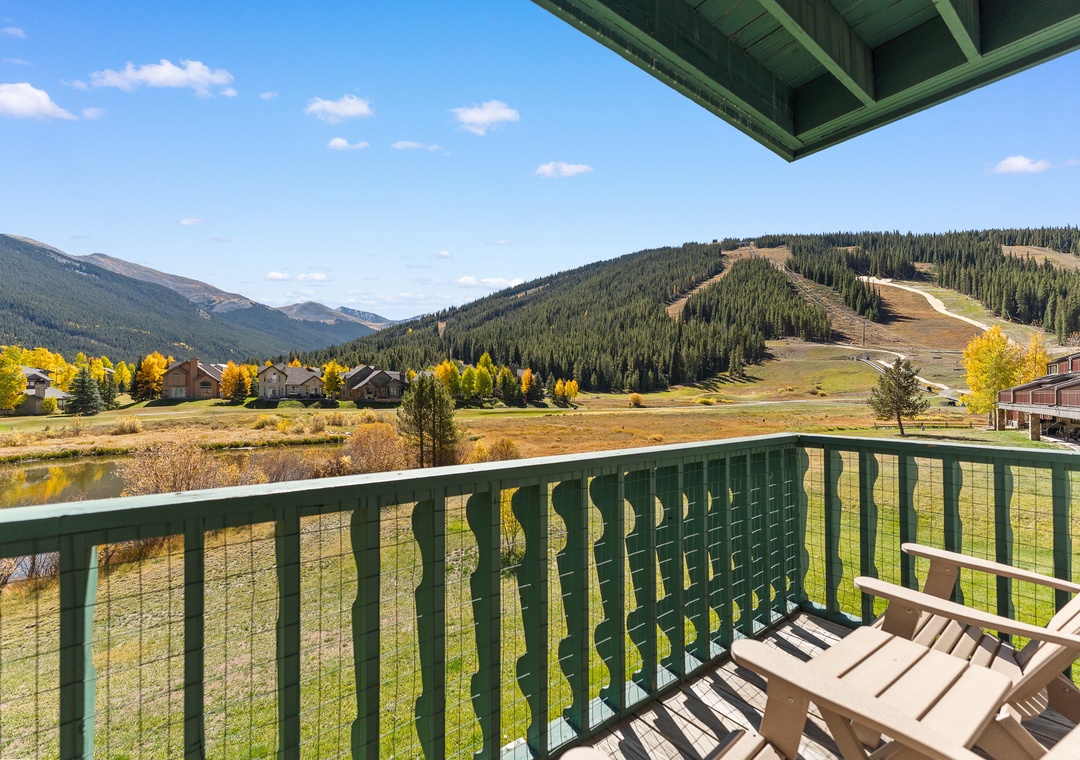 Mountain resort balcony offers stunning autumn views of ski slopes and colorful foliage in the peaceful valley below.