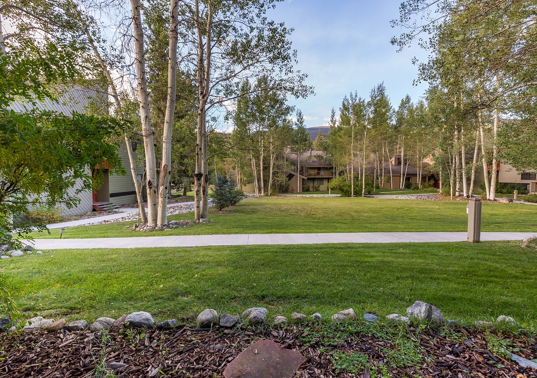 Peaceful residential neighborhood with mature aspen trees, manicured lawns, and mountain views creates a serene setting.