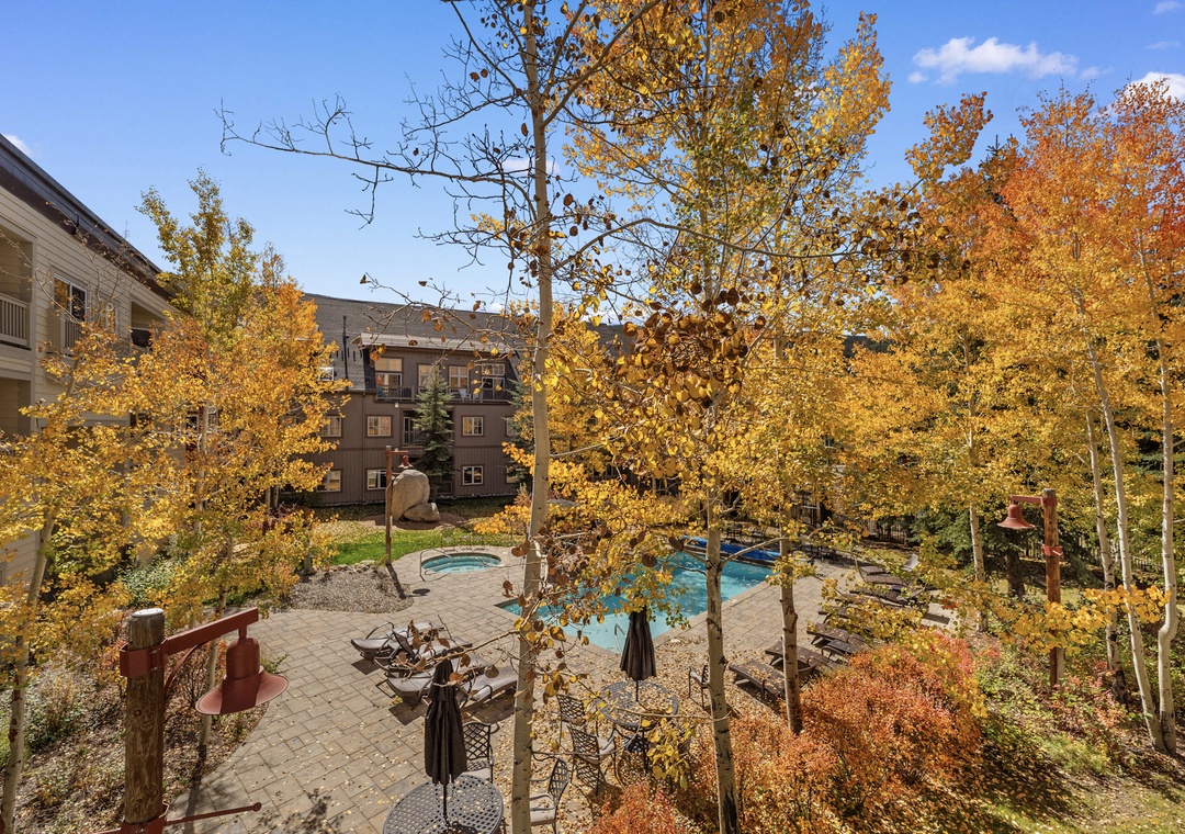 Resort pool area surrounded by vibrant autumn foliage and mountain lodge buildings.