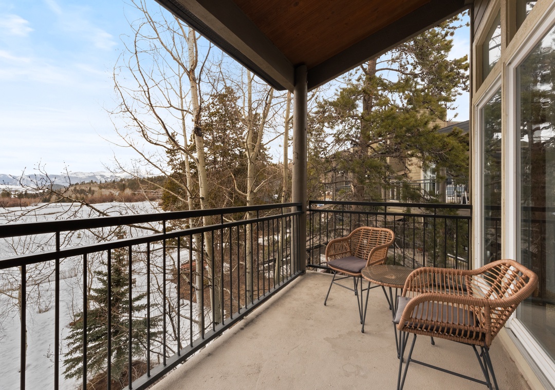 This covered balcony overlooks a tranquil natural landscape with evergreens, bare winter trees, and distant mountains—a peaceful setting near the property's entrance and surrounding area.
