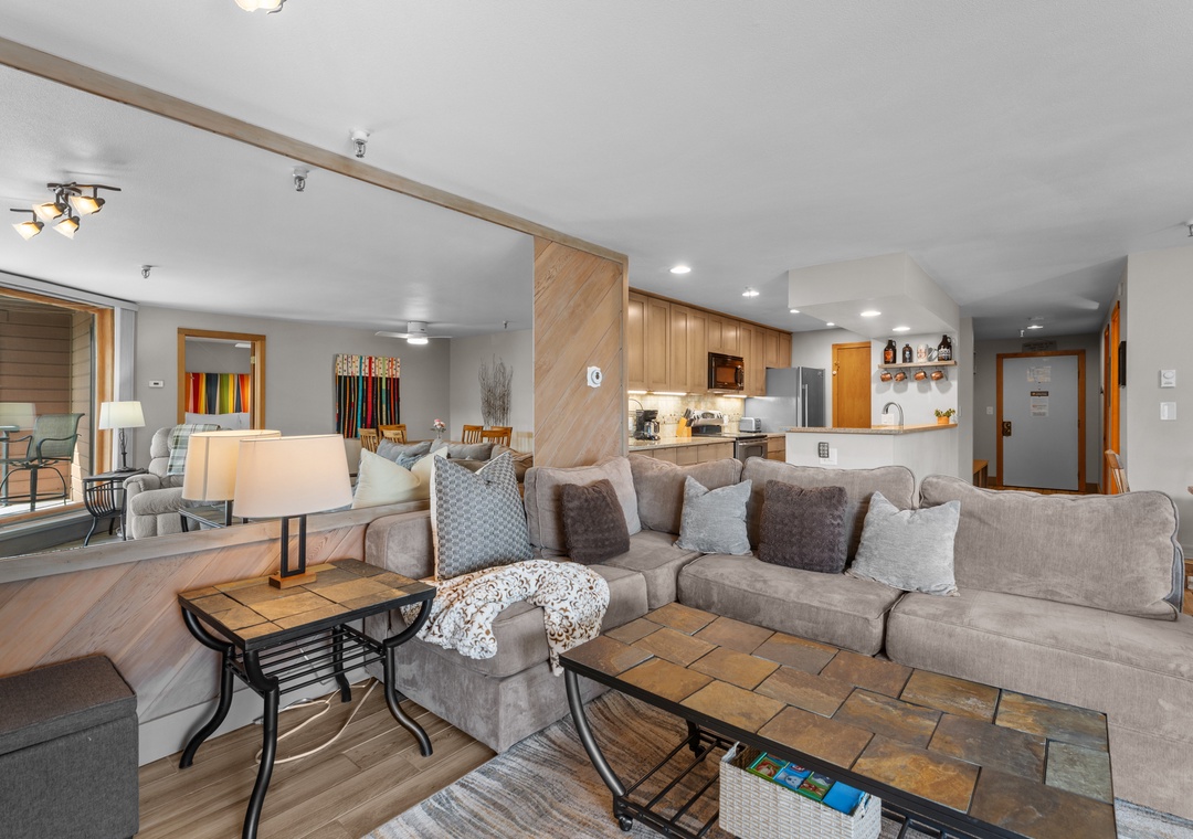 Step into your spacious open-plan living area with plush seating, warm wood accents, and a fully-equipped kitchen ready for your mountain getaway.