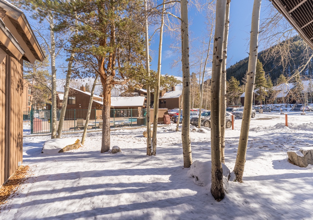 Snow-covered mountain resort property surrounded by aspen trees with convenient parking and winter mountain backdrop.