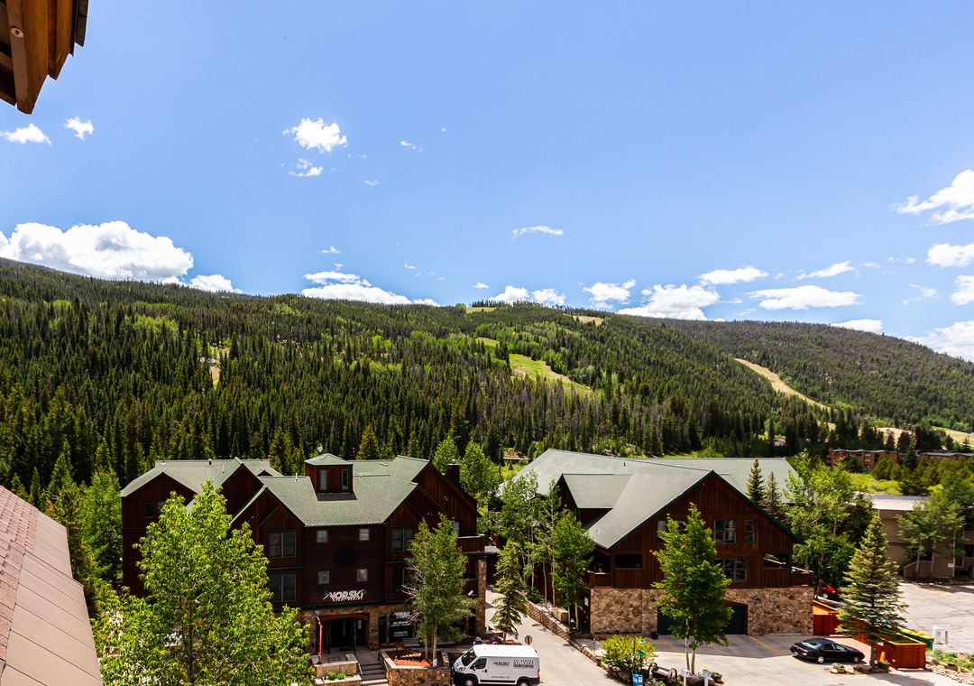 Mountain resort buildings nestled in a forested valley with ski slopes visible on the hillsides.