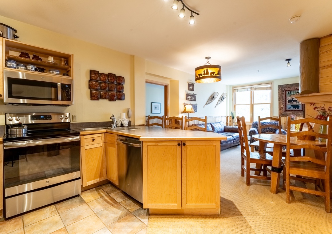 Your fully equipped kitchen flows seamlessly into the cozy dining area, perfect for preparing meals and gathering together after mountain adventures.