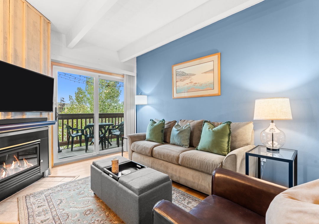 Settle into this inviting living space where blue walls and natural light create a peaceful retreat. The fireplace adds warmth while your private balcony opens to treetop views, perfect for morning coffee or evening relaxation.