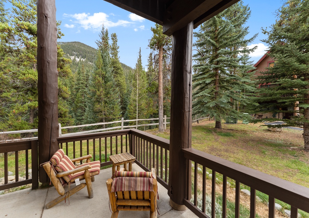Unwind on your private balcony with stunning mountain views, where comfortable seating invites peaceful moments among towering pines.