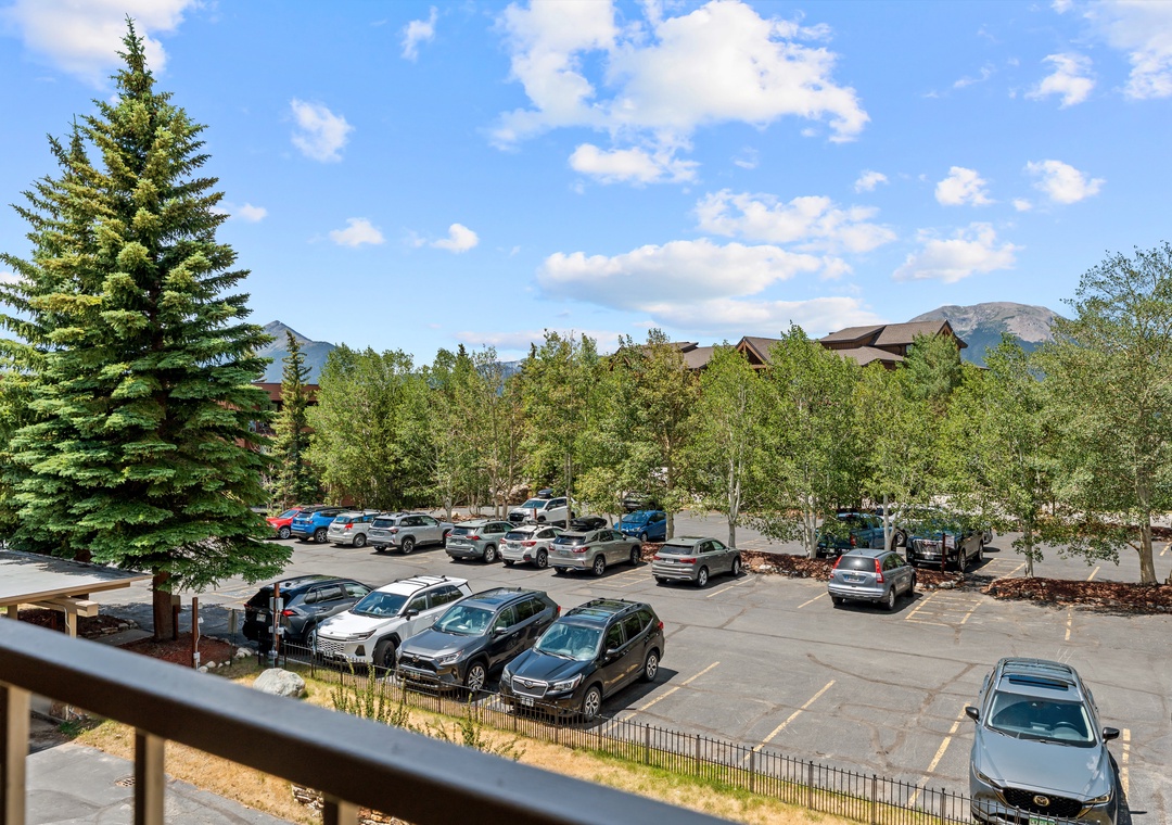 The property offers convenient parking with mountain scenery visible in the distance, surrounded by trees and open skies.