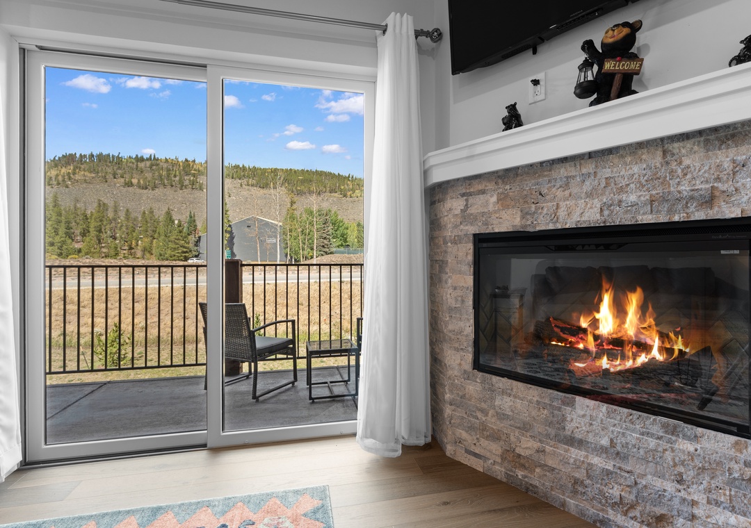 Step into your cozy retreat where a stunning stone fireplace sets the perfect mood, while sliding doors open to your private balcony framing breathtaking mountain views.