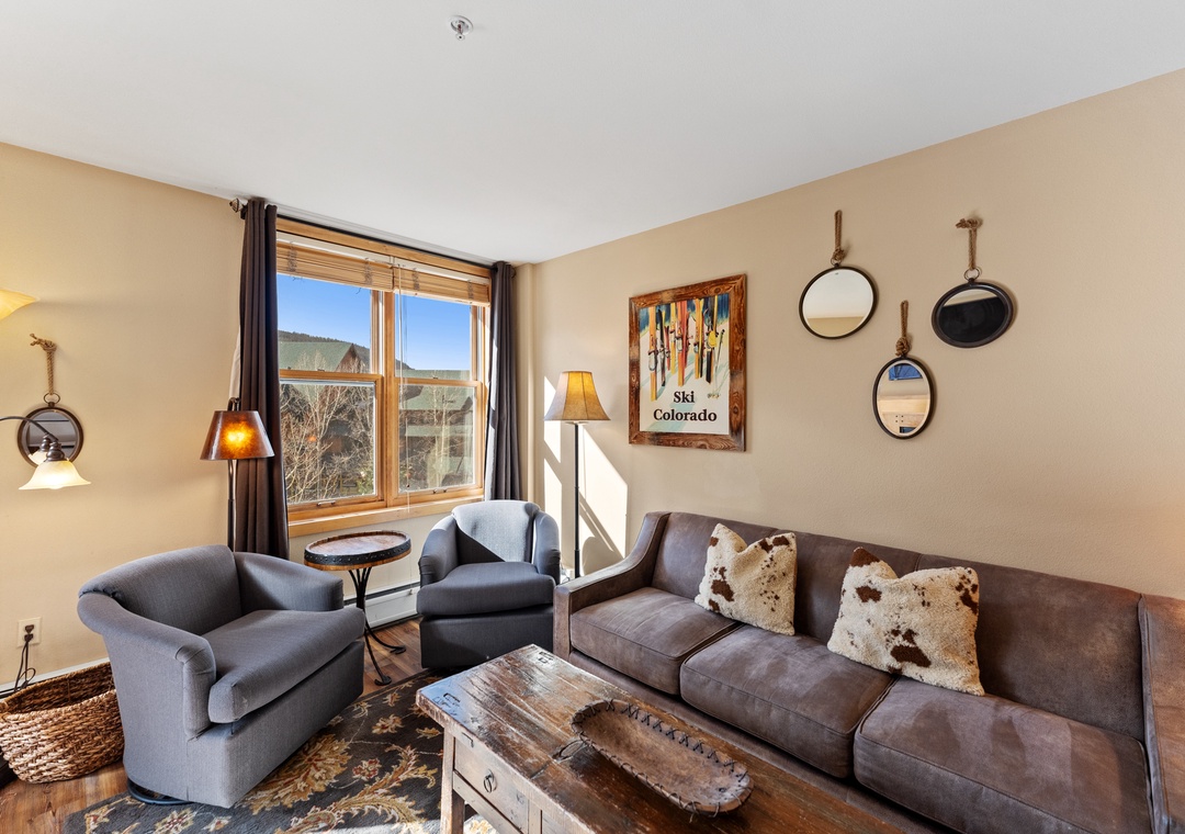 Settle into your cozy living room featuring plush seating, warm mountain-inspired decor, and bright windows overlooking scenic Colorado landscapes.