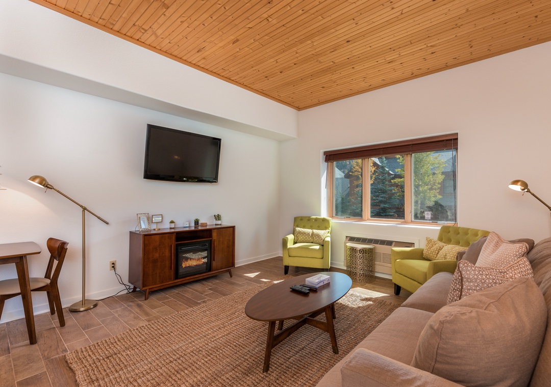 Sink into plush seating beneath warm wood ceilings while natural light filters through forest views, creating your perfect retreat.