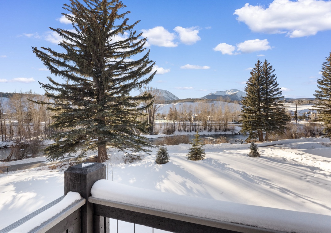 Snow-covered mountain landscape with evergreen trees and distant peaks visible from the property balcony.