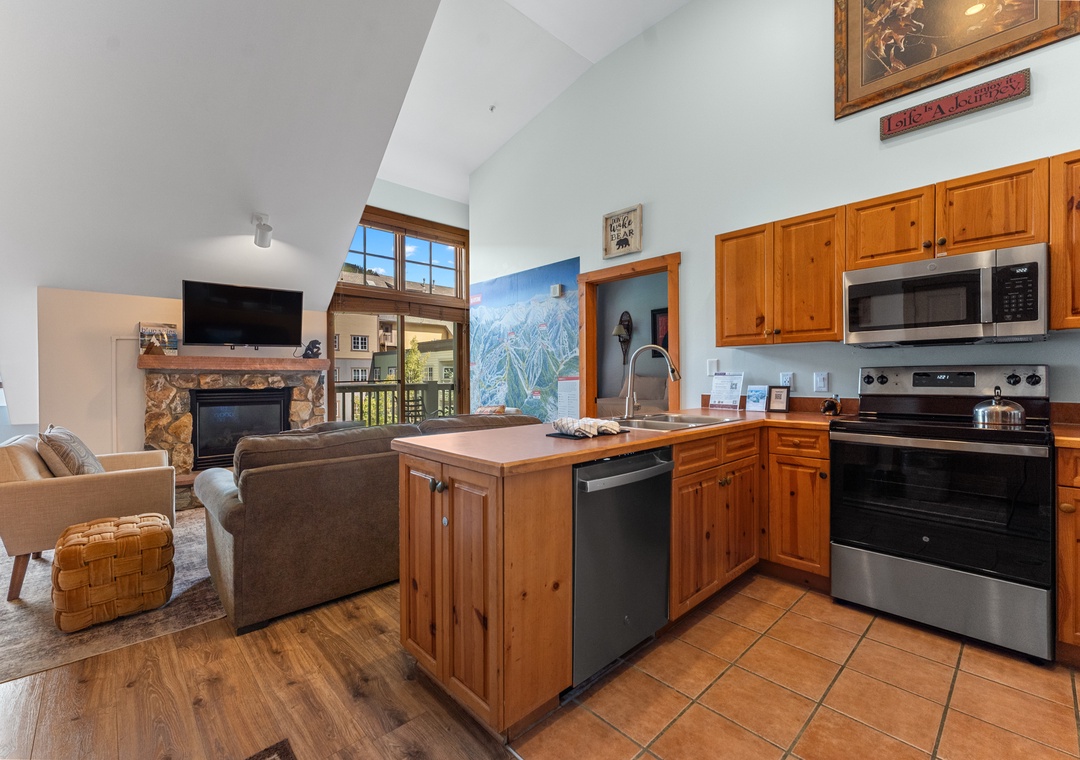 Your open-concept kitchen flows seamlessly into the living area, featuring warm wood cabinets, modern appliances, and a cozy fireplace for perfect mountain evenings.