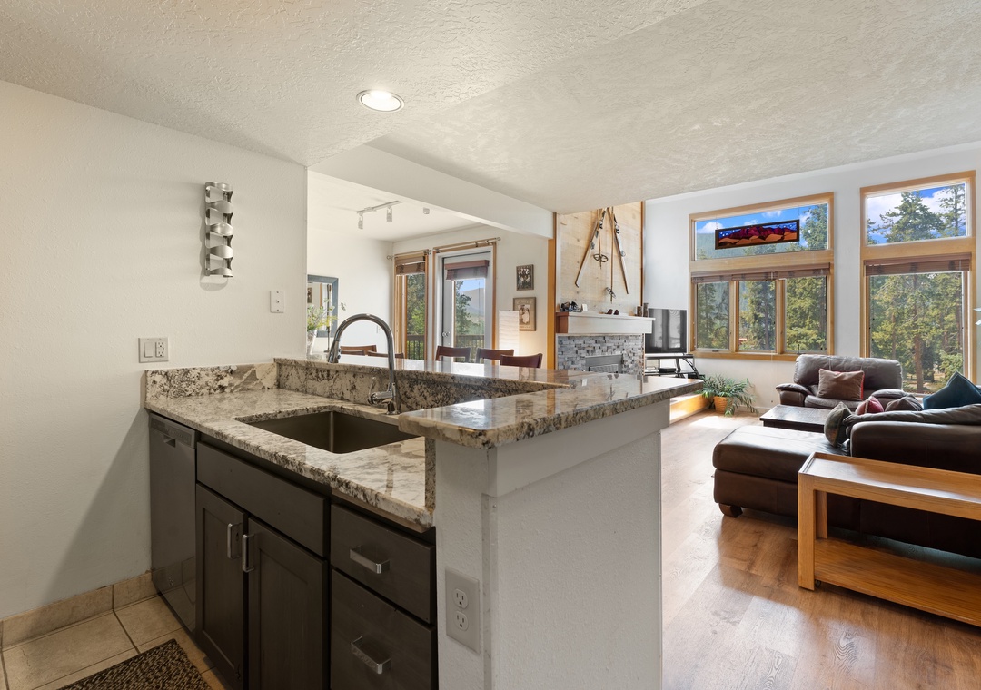 Step into your inviting open-concept retreat where natural light floods the space through expansive windows framing stunning forest views. The granite island anchors your fully-equipped kitchen, flowing seamlessly into the cozy living area.