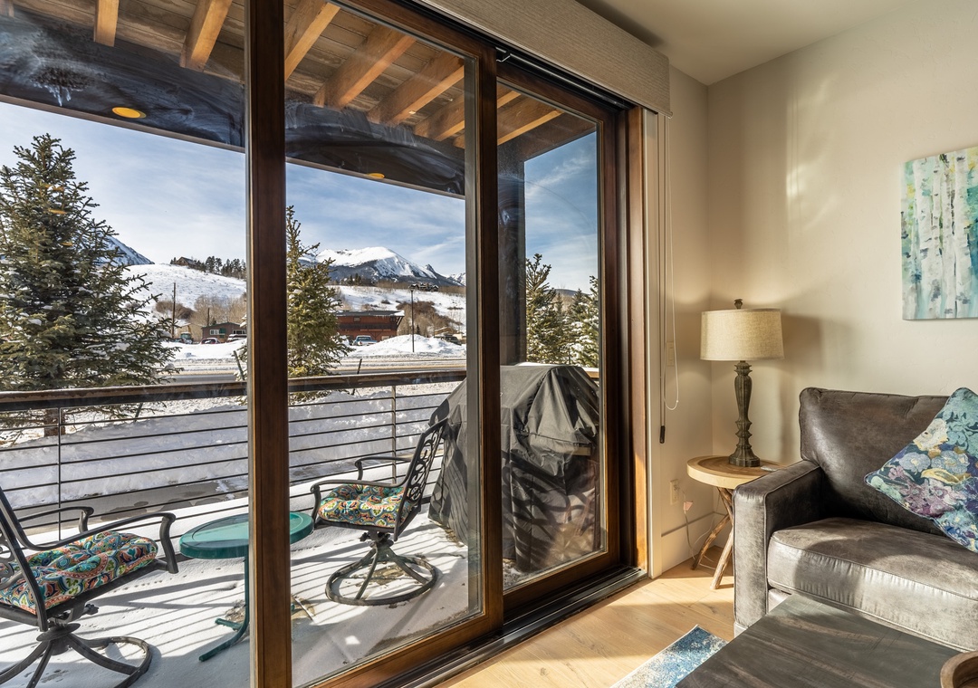 Cozy up in your comfortable armchair while enjoying breathtaking mountain views through floor-to-ceiling windows that flood the space with natural light.