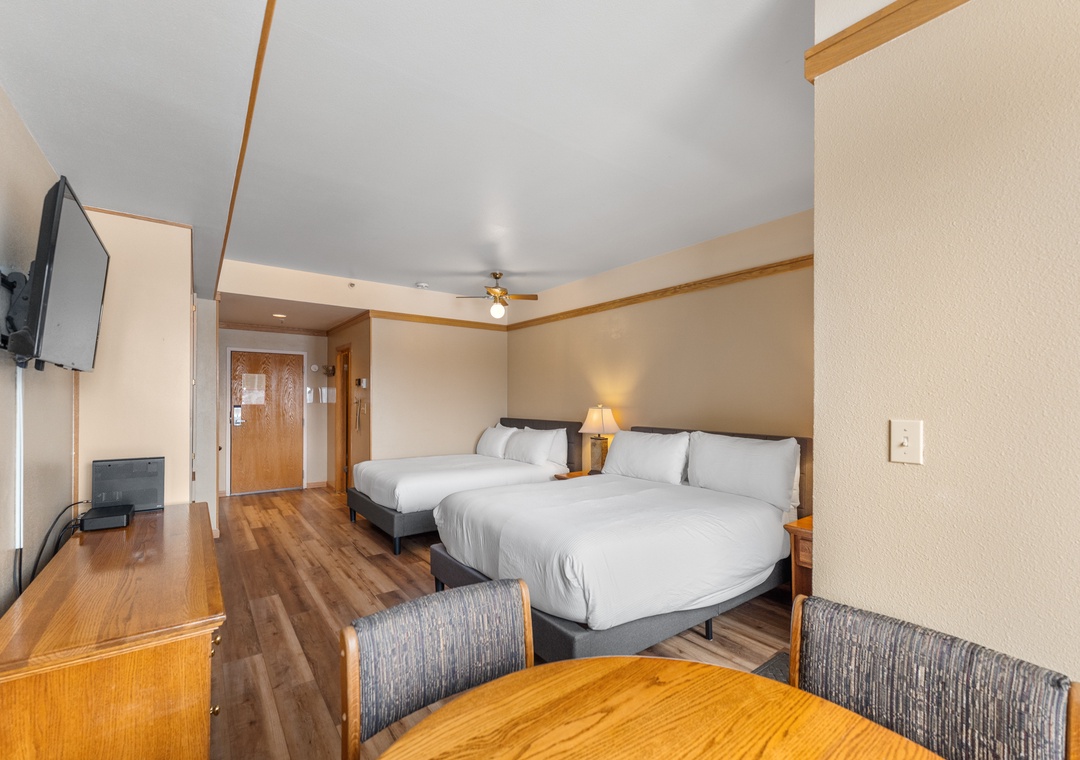 Relax in your spacious room with two queen beds, modern furnishings, and entertainment options for a comfortable stay.