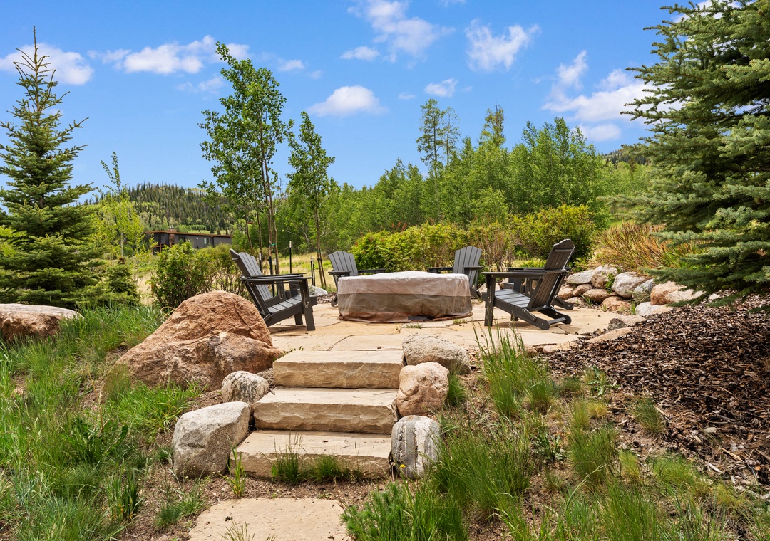 Gather around the covered fire pit with a cold drink in hand, soaking in mountain forest views while Adirondack chairs cradle you in comfort—your private retreat under endless skies.