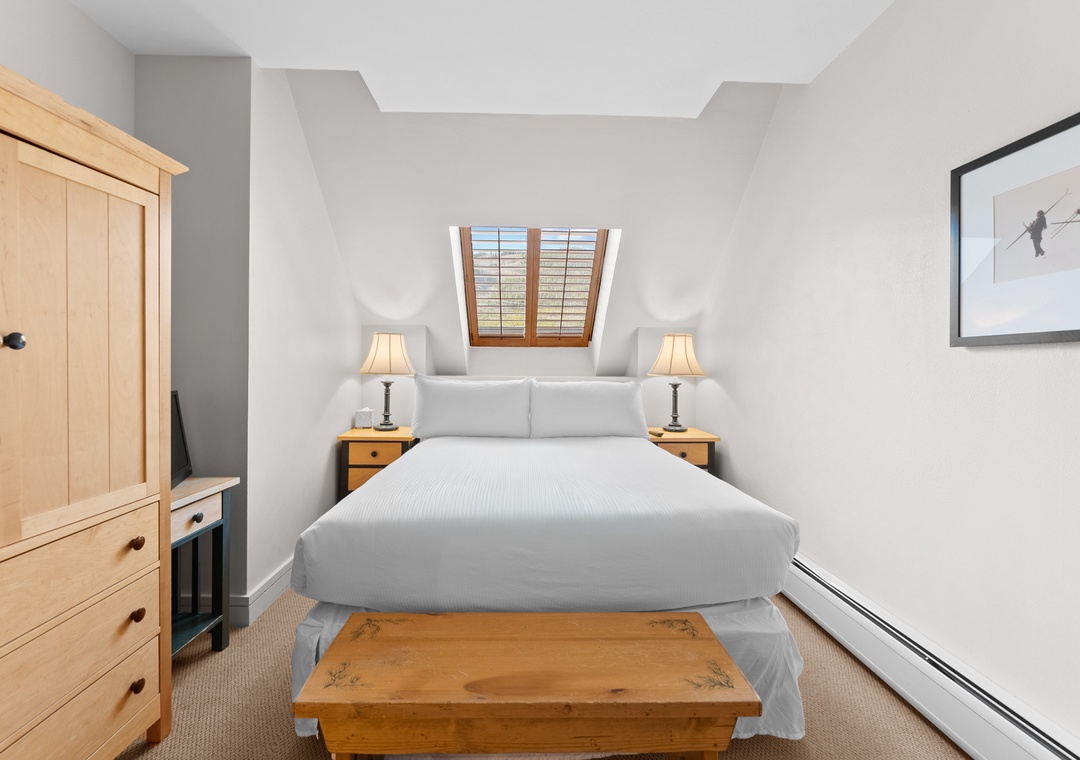 Slip into crisp white linens beneath a skylight in your cozy alpine retreat. Natural light pours in while warm wood furnishings create an inviting space for peaceful mountain dreams.