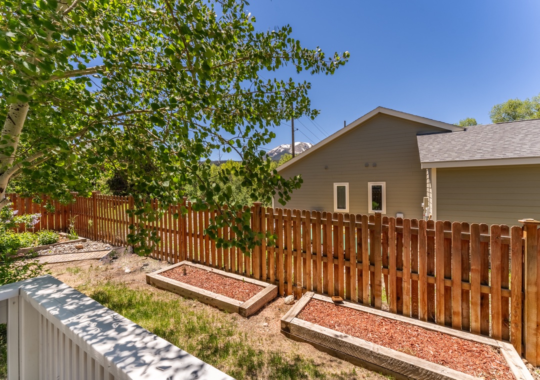 Private backyard with raised garden beds and mountain backdrop perfect for outdoor relaxation.
