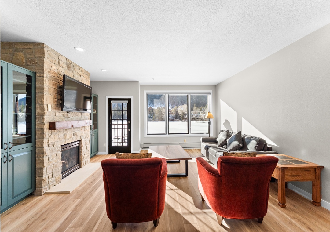 Relax in your bright living room with cozy fireplace, rich velvet chairs, and stunning mountain views through oversized windows.