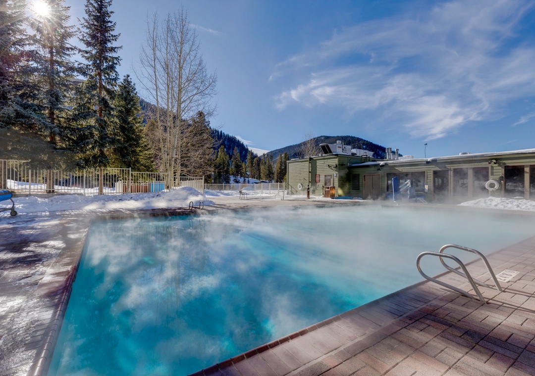Steam rises from this heated outdoor pool surrounded by snow-capped mountains, creating the perfect winter wellness retreat.