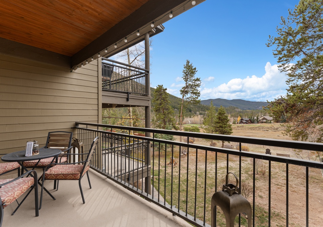 Sip your morning coffee while taking in sweeping mountain vistas from your private balcony, where cushioned seating awaits beneath a warm wood-beamed overhang.