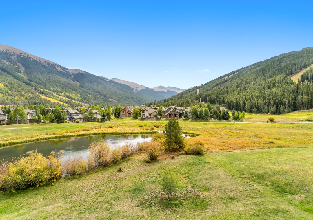 Stunning mountain valley setting with residential properties nestled among forest-covered slopes and meandering water features.