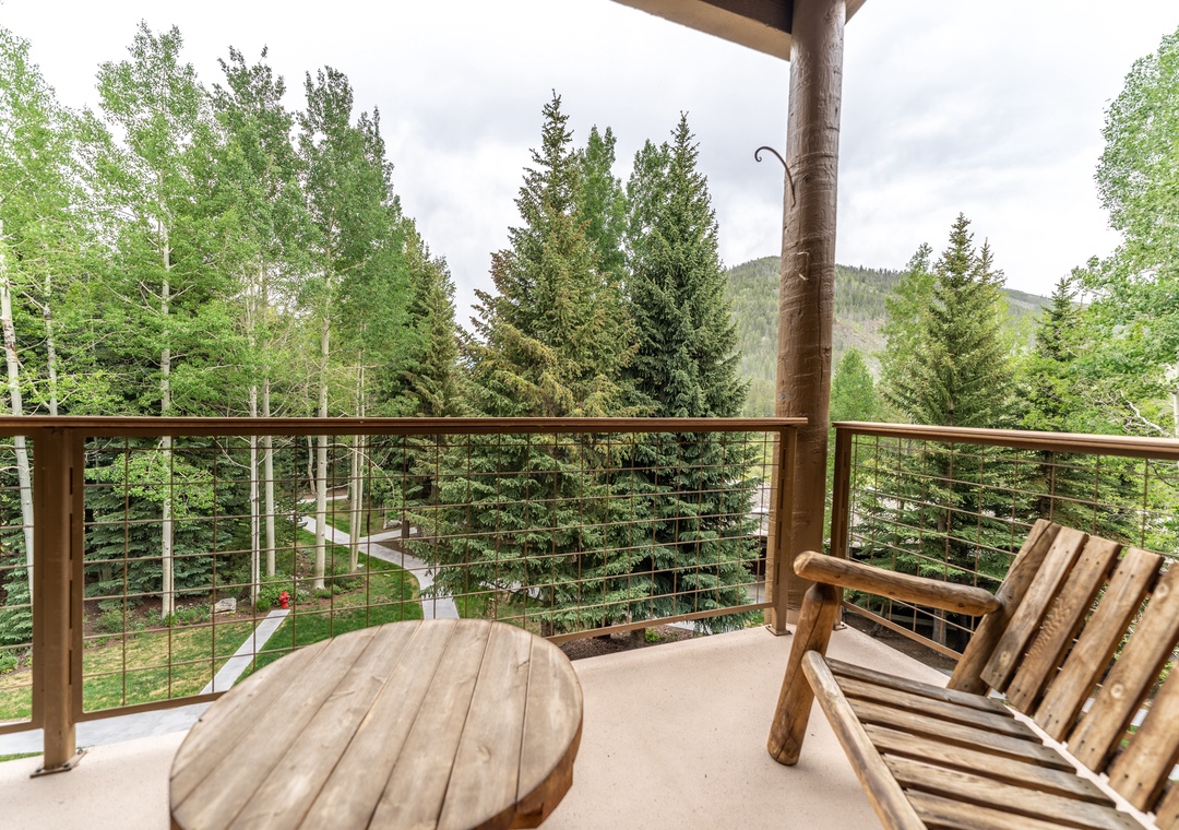 Unwind on your private balcony with mountain forest views, rustic wood furniture, and serene natural surroundings.