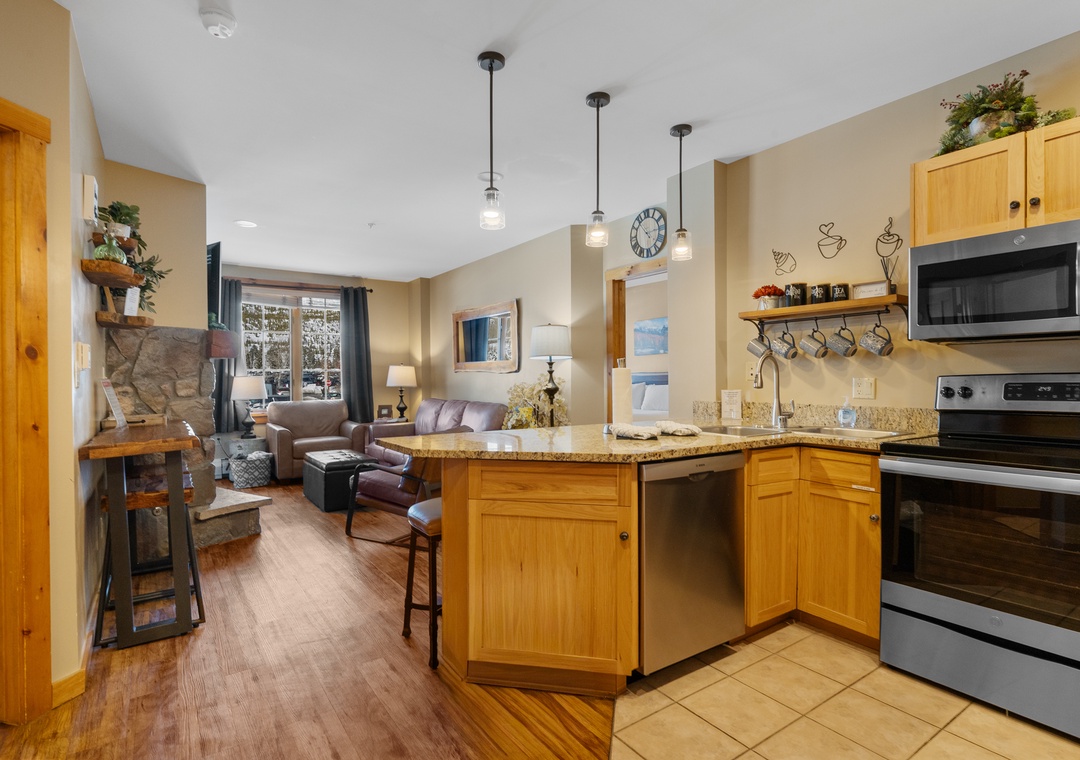 Relax in your open-concept living space with fully equipped kitchen, cozy fireplace, and warm mountain lodge atmosphere.