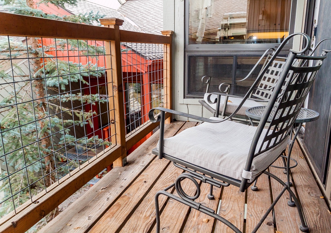 Unwind on your private balcony with comfortable seating overlooking charming rooftops and leafy neighborhood views.