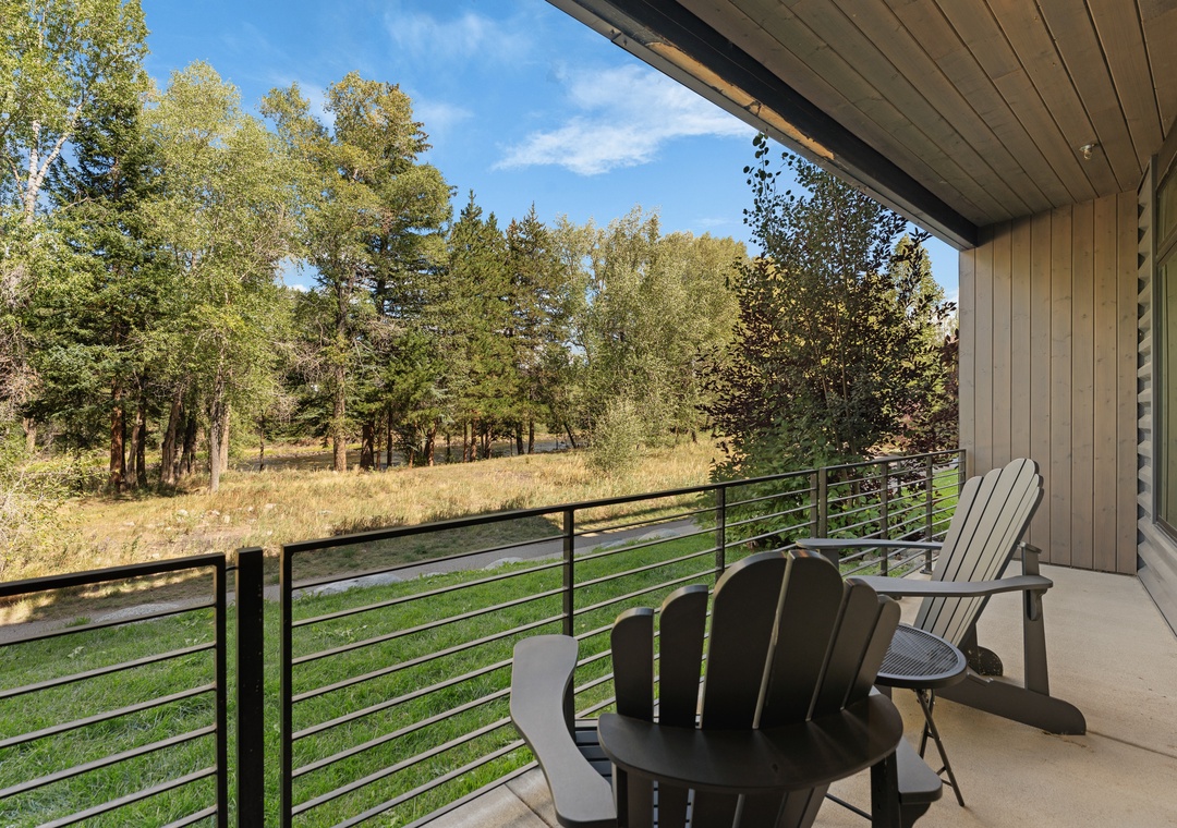 Settle into your private balcony with Adirondack chairs and take in peaceful views of open meadow and tall pines—your serene nature escape awaits.